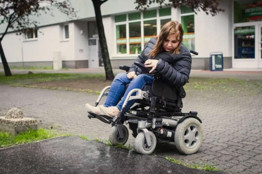 Natália sa so svojím vozíkom snaží prekonať nerovnosť na chodníku, ktorá jej komplikuje prejazd.